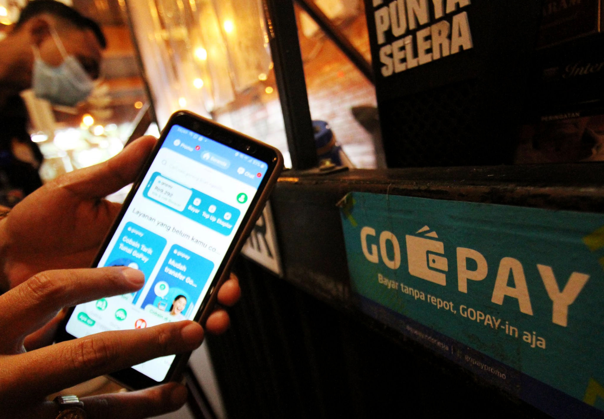 <p>Warga tengah melakukan transaksi pembayaran dengan menggunakan aplikasi Gopay di kawasan Tangerang. Foto: Panji Asmoro/TrenAsia</p>
