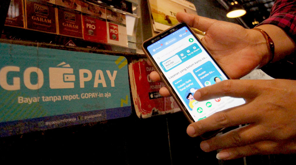 <p>Warga tengah melakukan transaksi pembayaran dengan menggunakan aplikasi Gopay di kawasan Tangerang. Foto: Panji Asmoro/TrenAsia</p>
