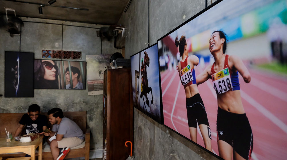 <p>Pengunjung berada diantara karya pewarta foto yang dipajang di kedai kopi “Ngopi di Halaman” di Jalan Pulo Kamboja, Kebayoran Lama, Jakarta, Kamis, 25 Februari 2021. Foto: Ismail Pohan/TrenAsia</p>
