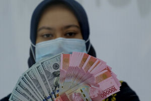 <p>Karyawati menunjukan mata uang Rupiah dan Dolar AS di Jakarta, Kamis, 18 Februari 2021. Foto: Ismail Pohan/TrenAsia</p>
