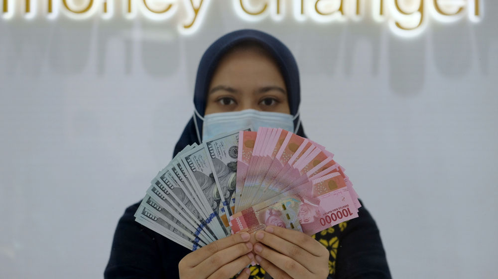 <p>Karyawati menunjukan mata uang Rupiah dan Dolar AS di Jakarta, Kamis, 18 Februari 2021. Foto: Ismail Pohan/TrenAsia</p>
