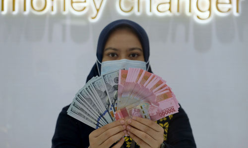 <p>Karyawati menunjukan mata uang Rupiah dan Dolar AS di Jakarta, Kamis, 18 Februari 2021. Foto: Ismail Pohan/TrenAsia</p>
