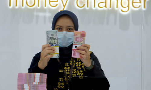 <p>Karyawati menunjukan mata uang Rupiah dan Dolar AS di Jakarta, Kamis, 18 Februari 2021. Foto: Ismail Pohan/TrenAsia</p>

