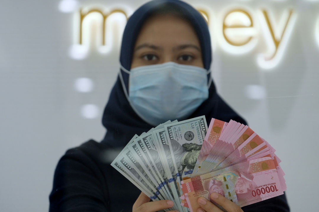 <p>Karyawati menunjukan mata uang Rupiah dan Dolar AS di Jakarta, Kamis, 18 Februari 2021. Foto: Ismail Pohan/TrenAsia</p>
