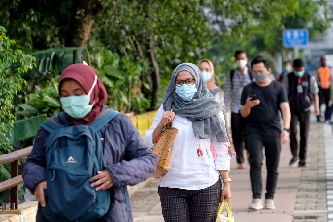 <p>Pekerja melintas pada jam pulang kerja di kawasan Jalan Jenderal Sudirman, Jakarta, Senin, 22 Februari 2021. Foto: Ismail Pohan/TrenAsia</p>
