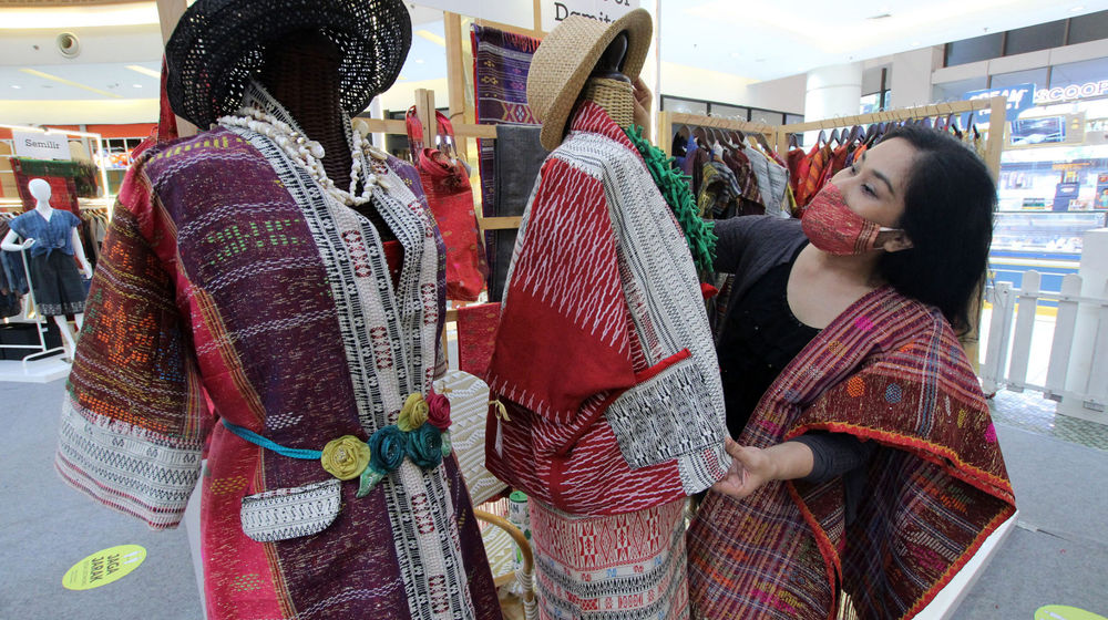 <p>Pekerja menata kain ulos di stand yang dipamerkan dalam Pekan Raya Produk Kreatif dan Kuliner Sumatera Utara di Gading Serpong, Tangerang, Banten, Rabu, 17 Februari 2021. Foto: Panji Asmoro/TrenAsia</p>
