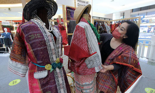 <p>Pekerja menata kain ulos di stand yang dipamerkan dalam Pekan Raya Produk Kreatif dan Kuliner Sumatera Utara di Gading Serpong, Tangerang, Banten, Rabu, 17 Februari 2021. Foto: Panji Asmoro/TrenAsia</p>
