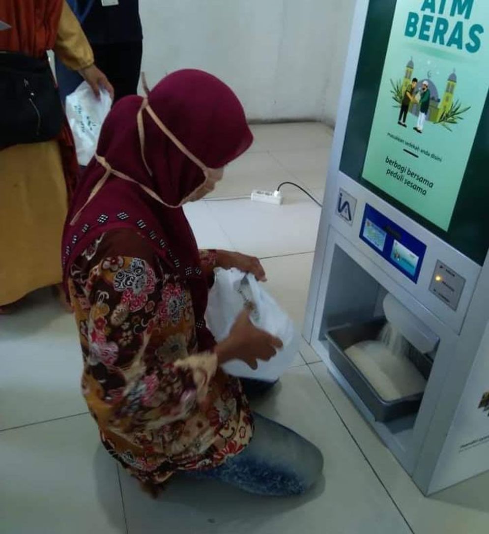 Salah seorang warga tengah menggunakan ATM beras yang ada di Masjid Nurul Iman Padang. Foto: ist