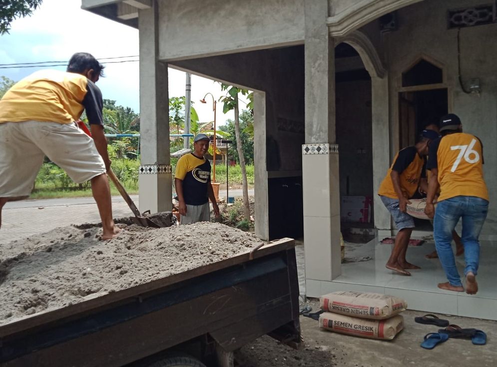 Anggota Karta Tunas Muda Jiwa tengah menurunkan material berupa semen dan pasir yang mereka sumbangkan untuk membantu pembangunan Mushola Dhakolah Jannah, di Dusun II, Desa Jiwan, Kecamatan Jiwan, Kabupaten Madiun, Jawa Timur.