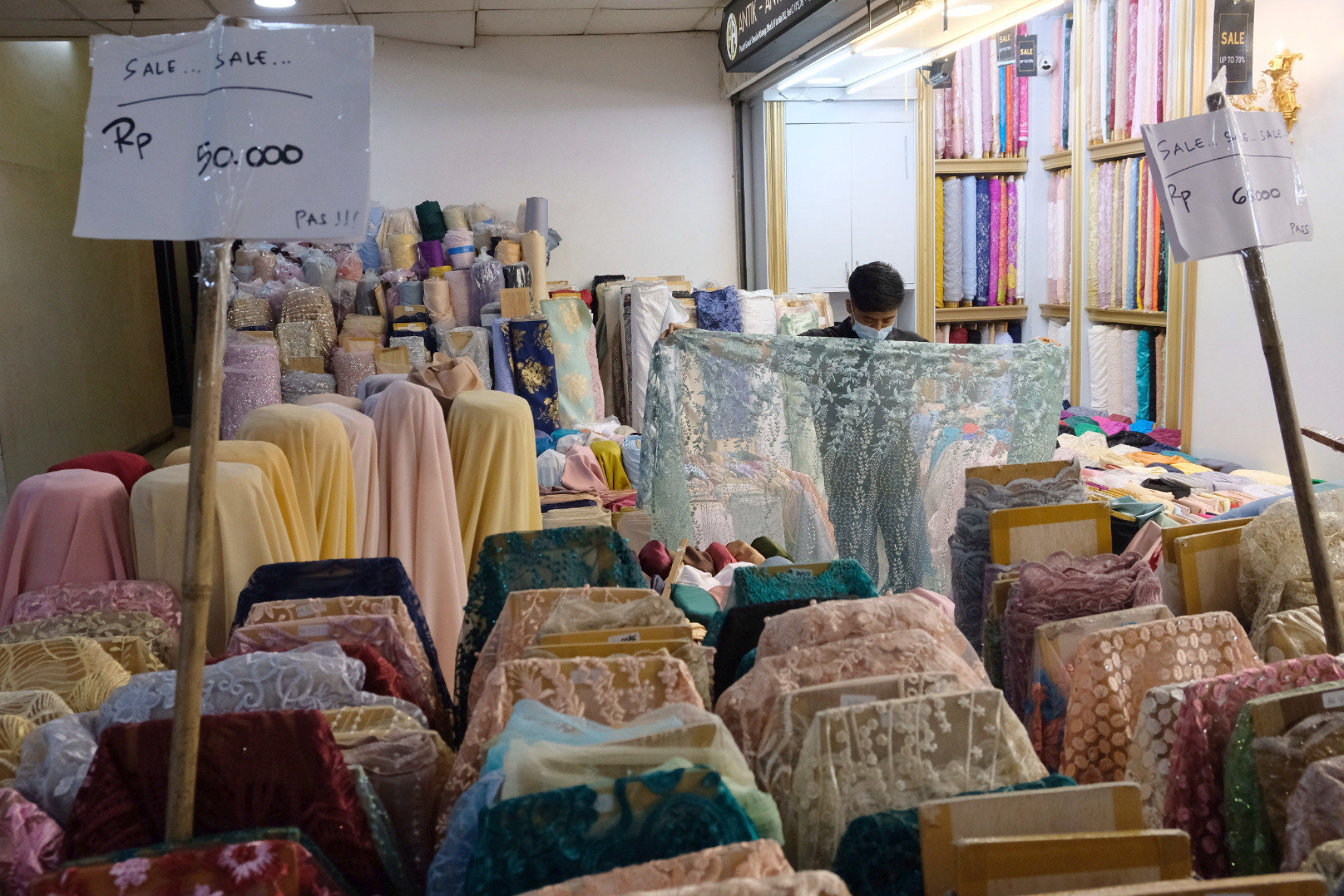 <p>Pedagang menunjukkan bahan kain di kios blok tekstil Pasar Tanah Abang, Jakarta, Rabu, 31 Maret 2021. Foto: Ismail Pohan/TrenAsia</p>
