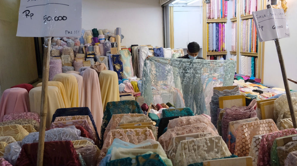 <p>Pedagang menunjukkan bahan kain di kios blok tekstil Pasar Tanah Abang, Jakarta, Rabu, 31 Maret 2021. Foto: Ismail Pohan/TrenAsia</p>
