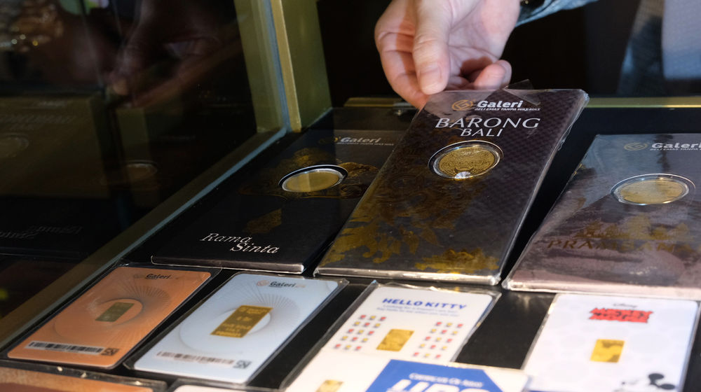 <p>Karyawati menunjukkan emas UBS di gerai Galeri 24 Pegadaian, Jakarta, Senin, 1 Maret 2021. Foto: Ismail Pohan/TrenAsia</p>
