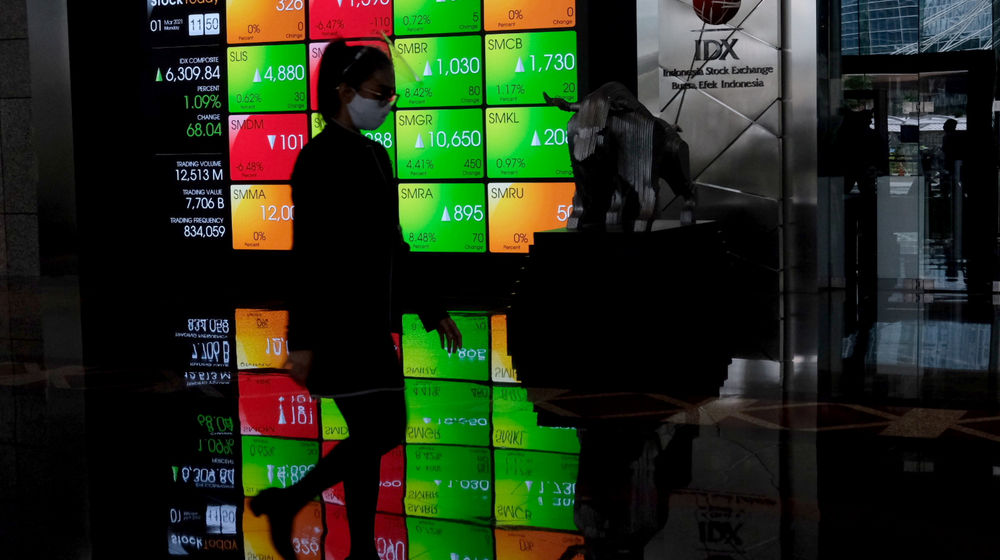 <p>Karyawan melintas dengan latar layar pergerakan indeks harga saham gabungan (IHSG) di Gedung Bursa Efek Indonesia (BEI), Jakarta, Senin, 1 Maret 2021. Foto: Ismail Pohan/TrenAsia</p>