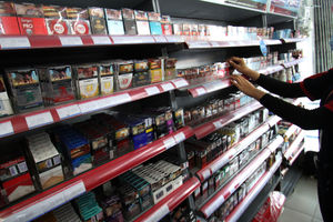 <p>Seorang karyawan tengah menata rokok dari berbagai jenis dan merk di sebuah etalase waralaba kawasan Cengkareng Jakarta Barat, Rabu 17 Maret 2021. Foto: Panji Asmoro/TrenAsia</p>
