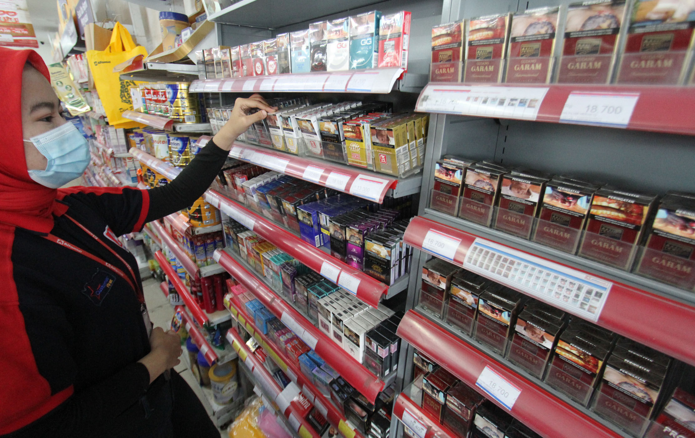 <p>Seorang karyawan tengah menata rokok dari berbagai jenis dan merk di sebuah etalase waralaba kawasan Cengkareng Jakarta Barat, Rabu 17 Maret 2021. Foto: Panji Asmoro/TrenAsia</p>
