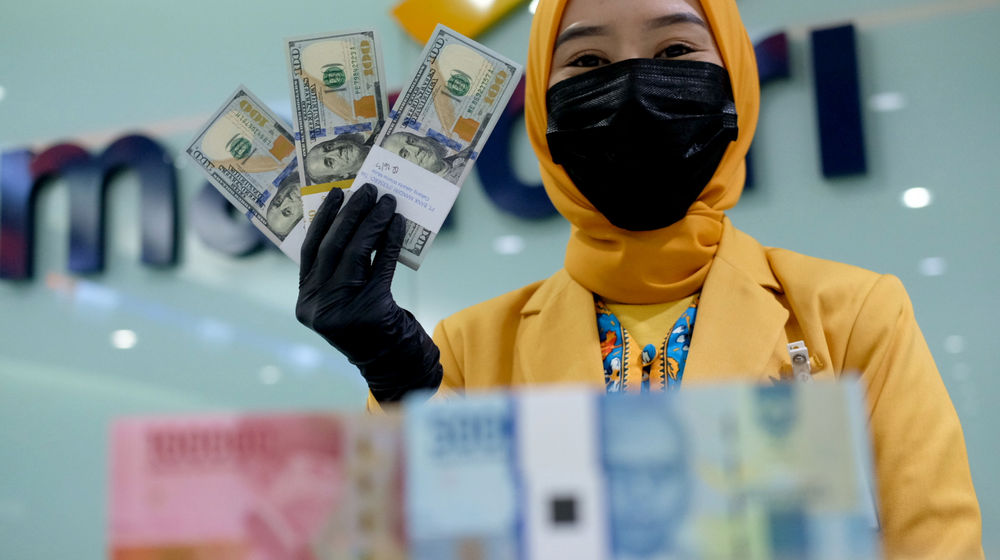 <p>Karyawati menunjukkan mata uang rupiah dan dolar di kantor cabang Bank Mandiri, Jakarta, Senin, 22 Maret 2021. Foto: Ismail Pohan/TrenAsia</p>
