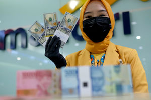 <p>Karyawati menunjukkan mata uang rupiah dan dolar di kantor cabang Bank Mandiri, Jakarta, Senin, 22 Maret 2021. Foto: Ismail Pohan/TrenAsia</p>
