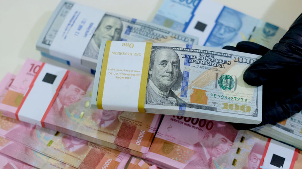 <p>Karyawati menunjukkan mata uang rupiah dan dolar di kantor cabang Bank Mandiri, Jakarta, Senin, 22 Maret 2021. Foto: Ismail Pohan/TrenAsia</p>
