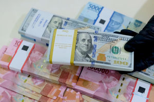 <p>Karyawati menunjukkan mata uang rupiah dan dolar di kantor cabang Bank Mandiri, Jakarta, Senin, 22 Maret 2021. Foto: Ismail Pohan/TrenAsia</p>