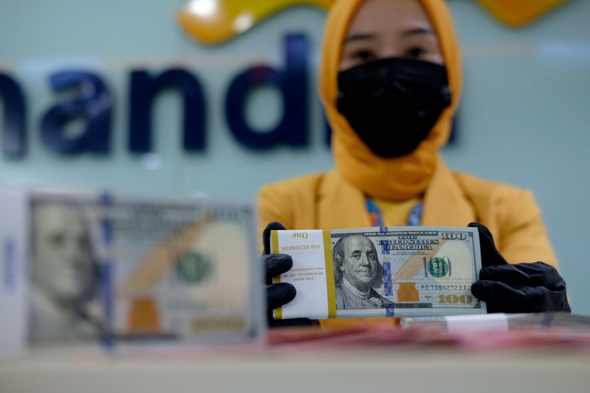 <p>Karyawati menunjukkan mata uang dolar di kantor cabang Bank Mandiri, Jakarta, Senin, 22 Maret 2021. Foto: Ismail Pohan/TrenAsia</p>
