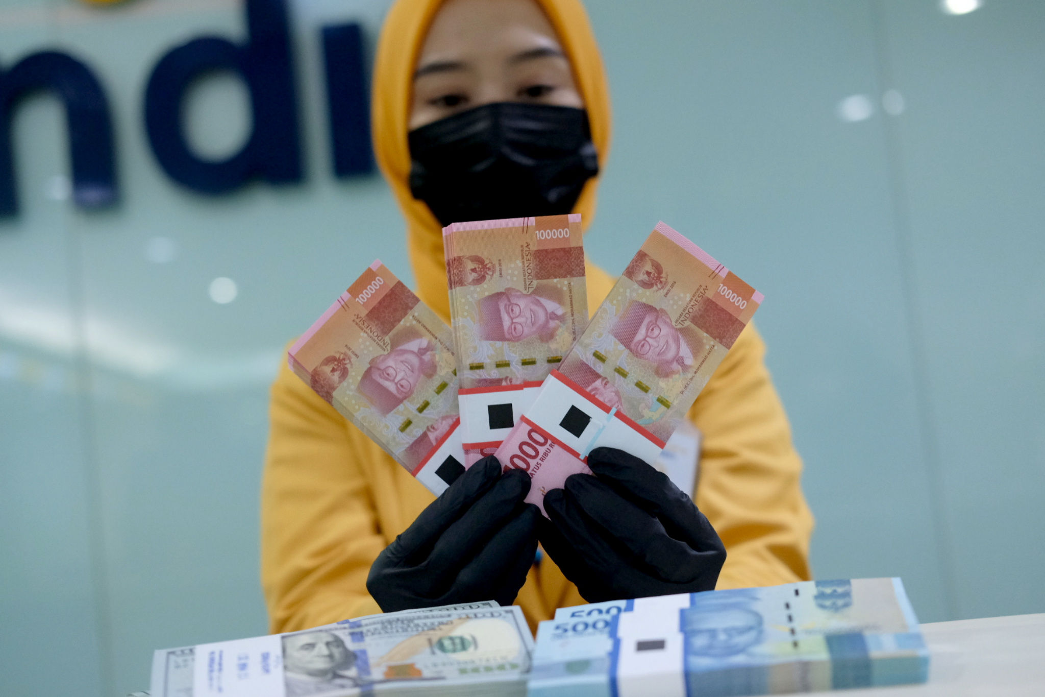 <p>Karyawati menunjukkan mata uang rupiah dan dolar di kantor cabang Bank Mandiri, Jakarta, Senin, 22 Maret 2021. Foto: Ismail Pohan/TrenAsia</p>
