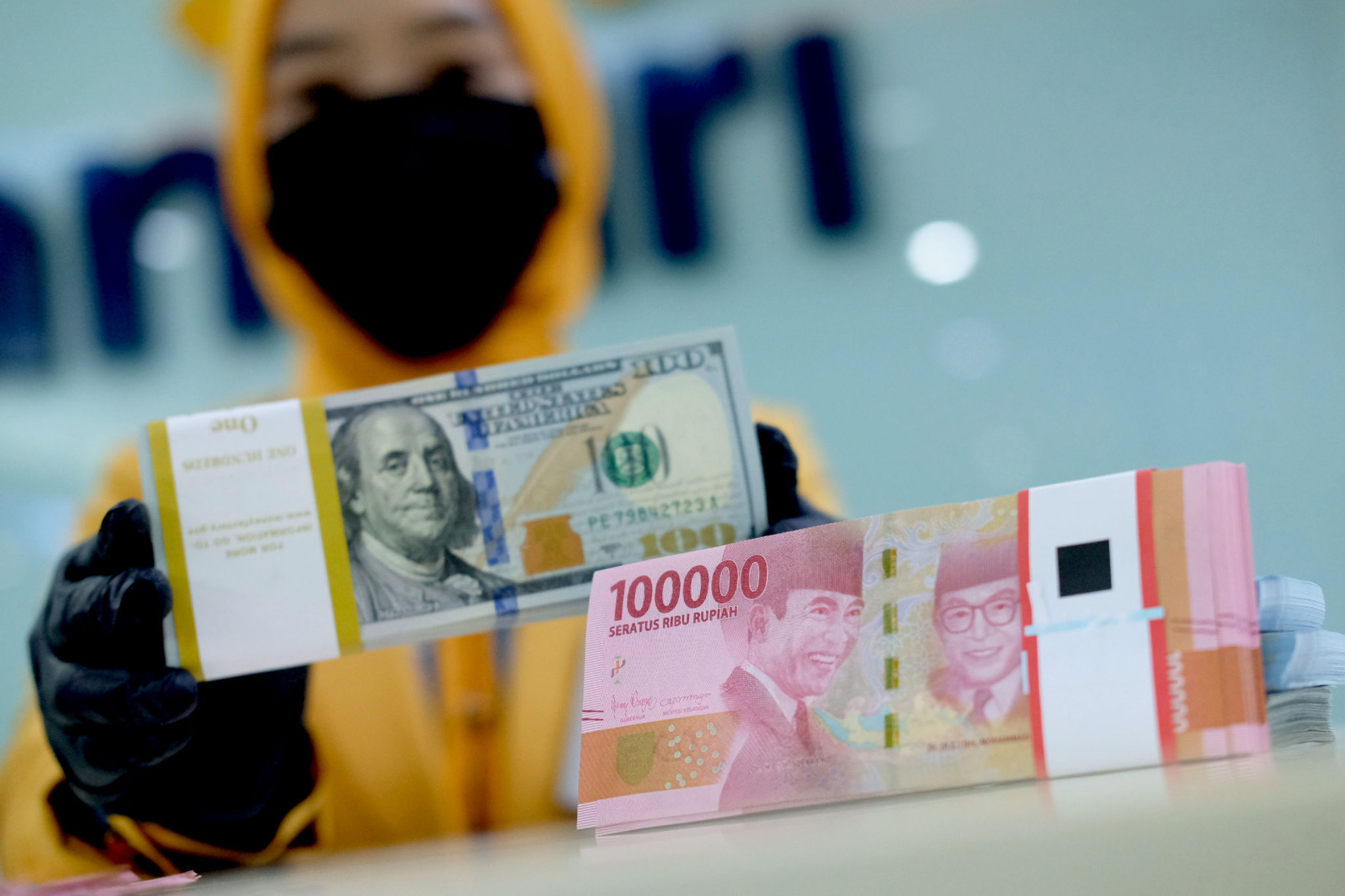 <p>Karyawati menunjukkan mata uang rupiah dan dolar di kantor cabang Bank Mandiri, Jakarta, Senin, 22 Maret 2021. Foto: Ismail Pohan/TrenAsia</p>
