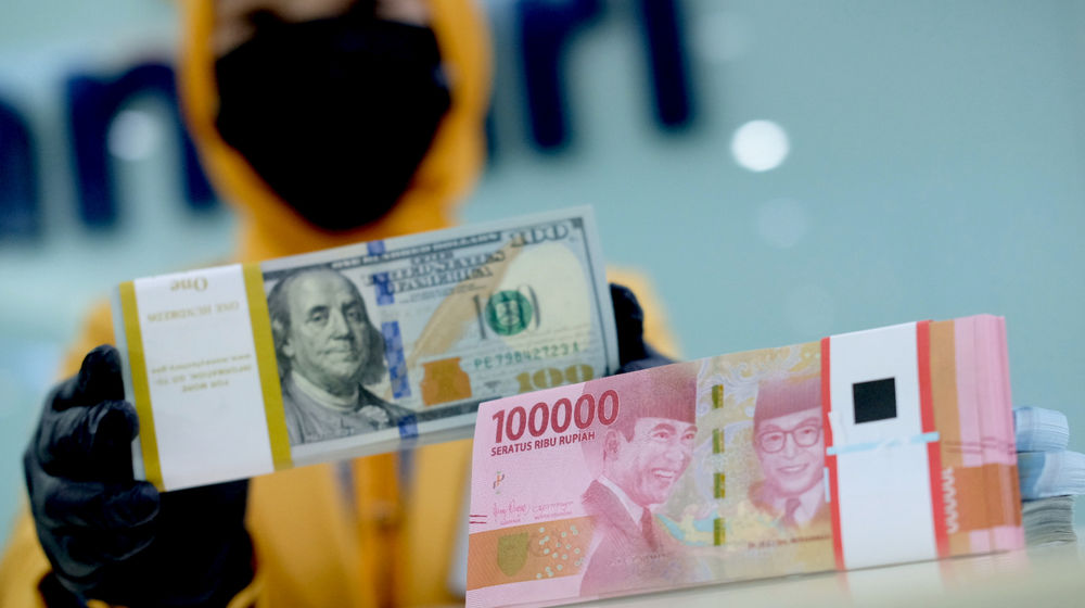 <p>Karyawati menunjukkan mata uang rupiah dan dolar di kantor cabang Bank Mandiri, Jakarta, Senin, 22 Maret 2021. Foto: Ismail Pohan/TrenAsia</p>
