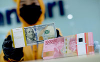 <p>Karyawati menunjukkan mata uang rupiah dan dolar di kantor cabang Bank Mandiri, Jakarta, Senin, 22 Maret 2021. Foto: Ismail Pohan/TrenAsia</p>
