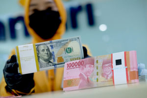 <p>Karyawati menunjukkan mata uang rupiah dan dolar di kantor cabang Bank Mandiri, Jakarta, Senin, 22 Maret 2021. Foto: Ismail Pohan/TrenAsia</p>
