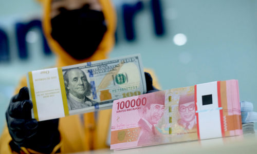 <p>Karyawati menunjukkan mata uang rupiah dan dolar di kantor cabang Bank Mandiri, Jakarta, Senin, 22 Maret 2021. Foto: Ismail Pohan/TrenAsia</p>
