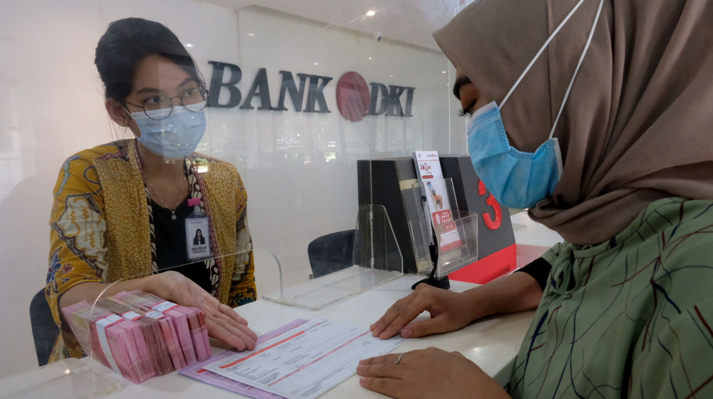 <p>Karyawan melayani nasabah di salah satu Kantor Cabang Bank DKI, Jakarta, Jum’at, 26 Maret 2021. Foto: Ismail Pohan/TrenAsia</p>
