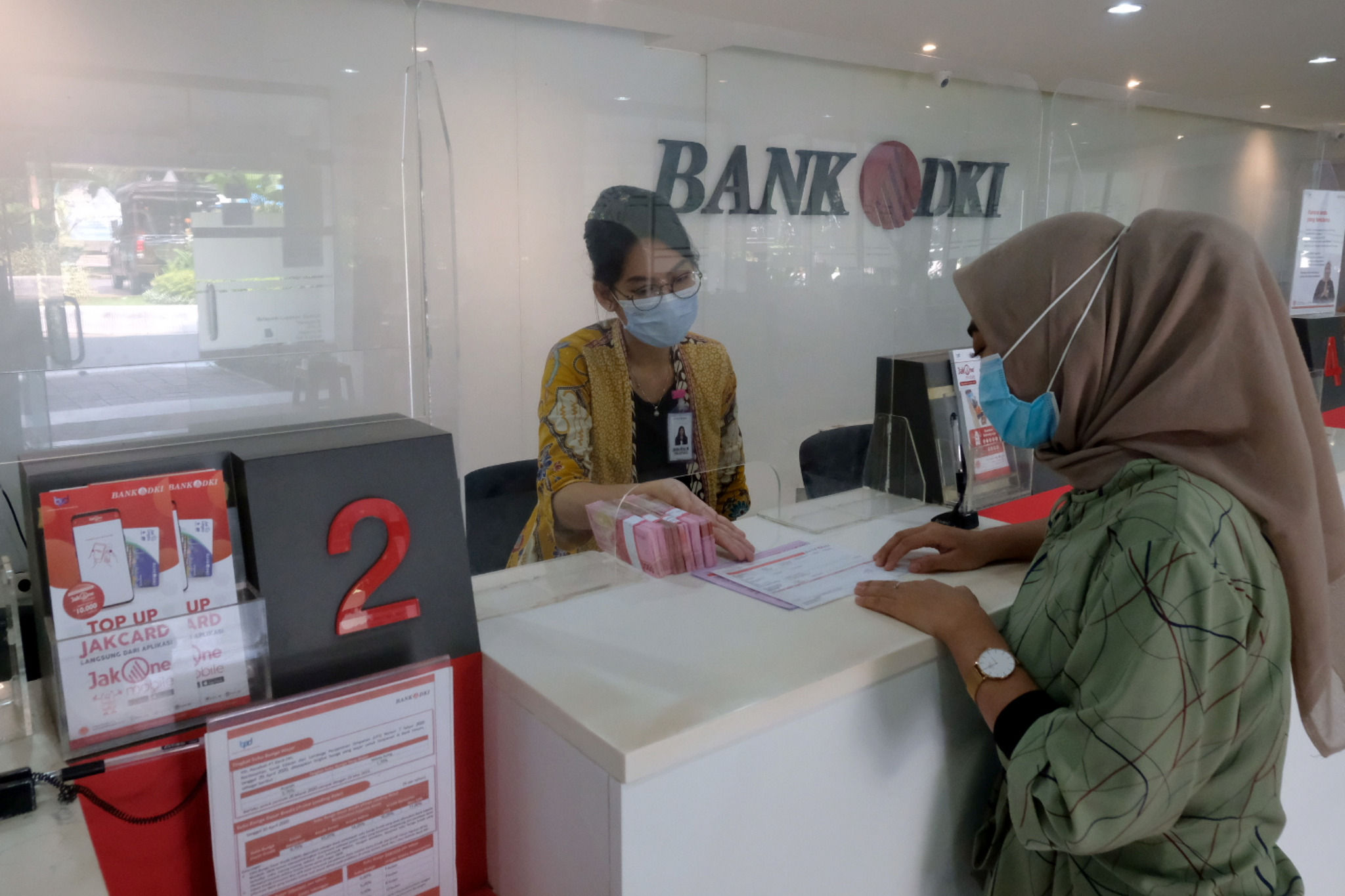 <p>Karyawan melayani nasabah di salah satu Kantor Cabang Bank DKI, Jakarta, Jum&#8217;at, 26 Maret 2021. Foto: Ismail Pohan/TrenAsia</p>

