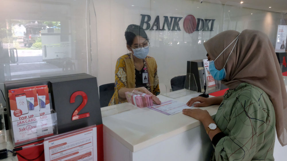 <p>Karyawan melayani nasabah di salah satu Kantor Cabang Bank DKI, Jakarta, Jum’at, 26 Maret 2021. Foto: Ismail Pohan/TrenAsia</p>
