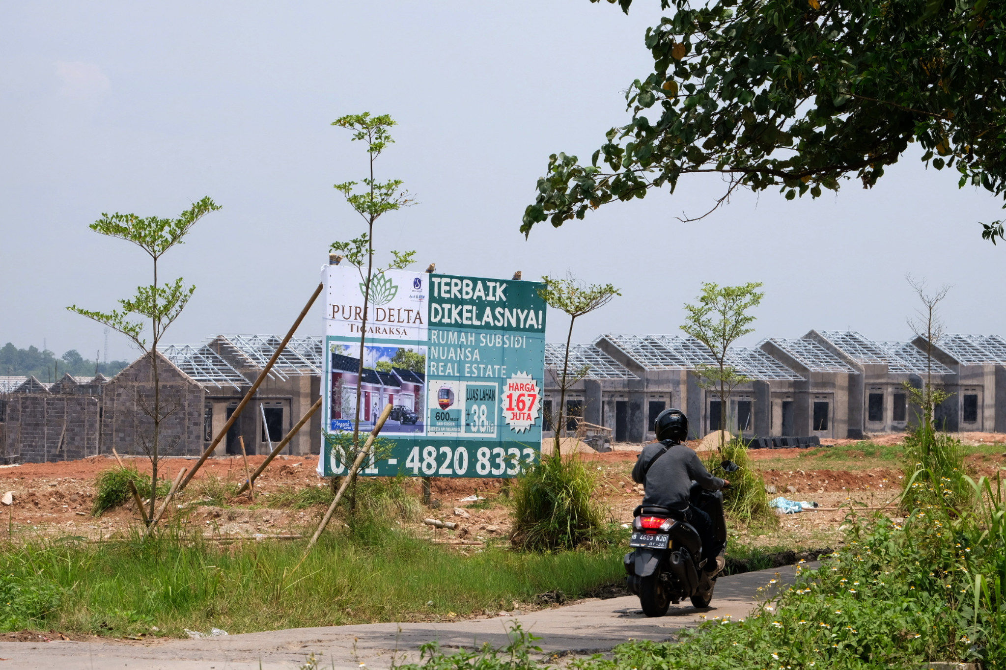 <p>Warga melintas di dekat proyek pembangunan rumah subsidi di kawasan Tigaraksa, Tangerang, Senin, 28 Maret 2021. Foto: Ismail Pohan/TrenAsia</p>
