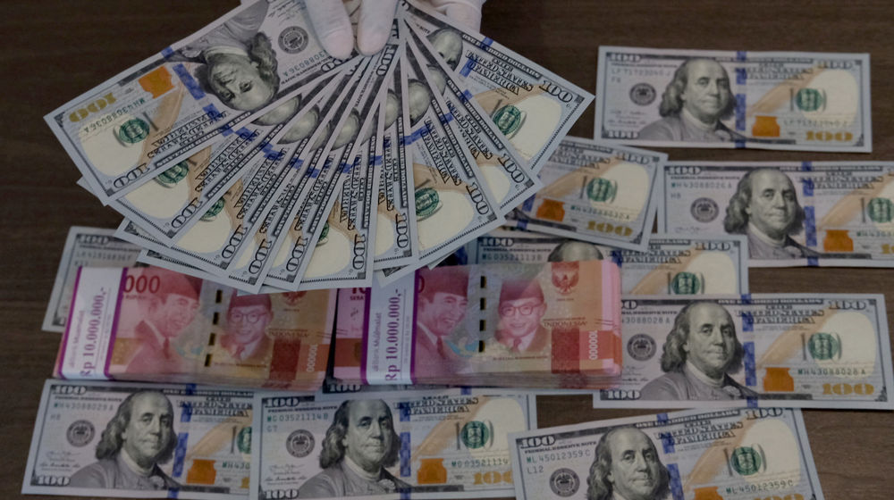 <p>Karyawati menunjukkan mata uang Dolar Amerika dan Rupiah di salah satu teller bank, di Jakarta, Rabu, 3 Maret 2021. Foto: Ismail Pohan/TrenAsia</p>
