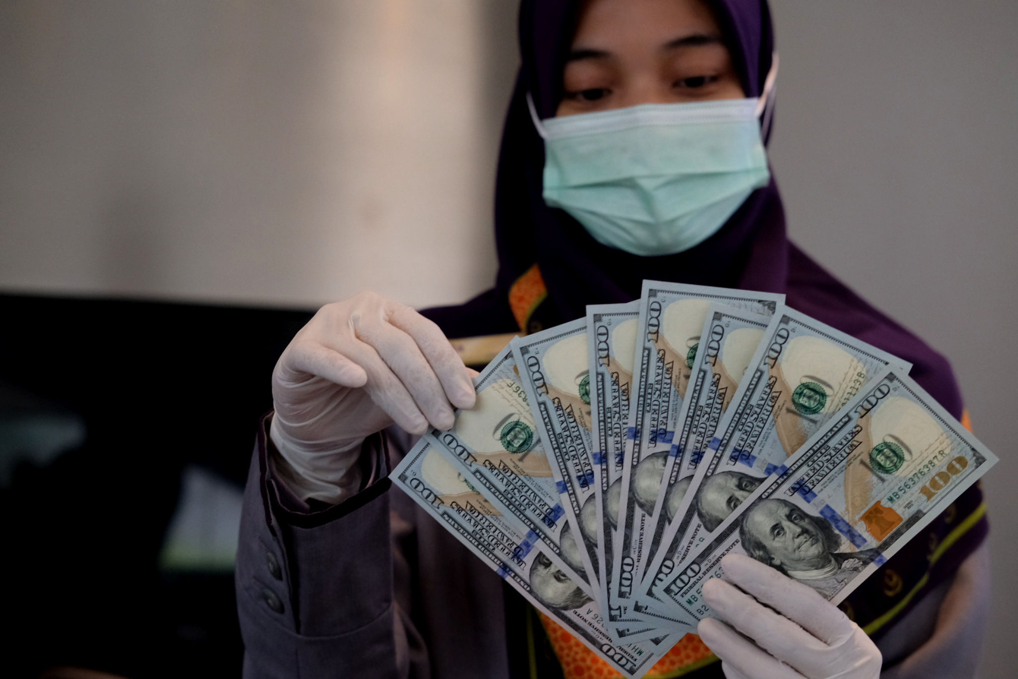 <p>Karyawati menunjukkan mata uang Dolar Amerika di salah satu teller bank, di Jakarta, Rabu, 3 Maret 2021. Foto: Ismail Pohan/TrenAsia</p>
