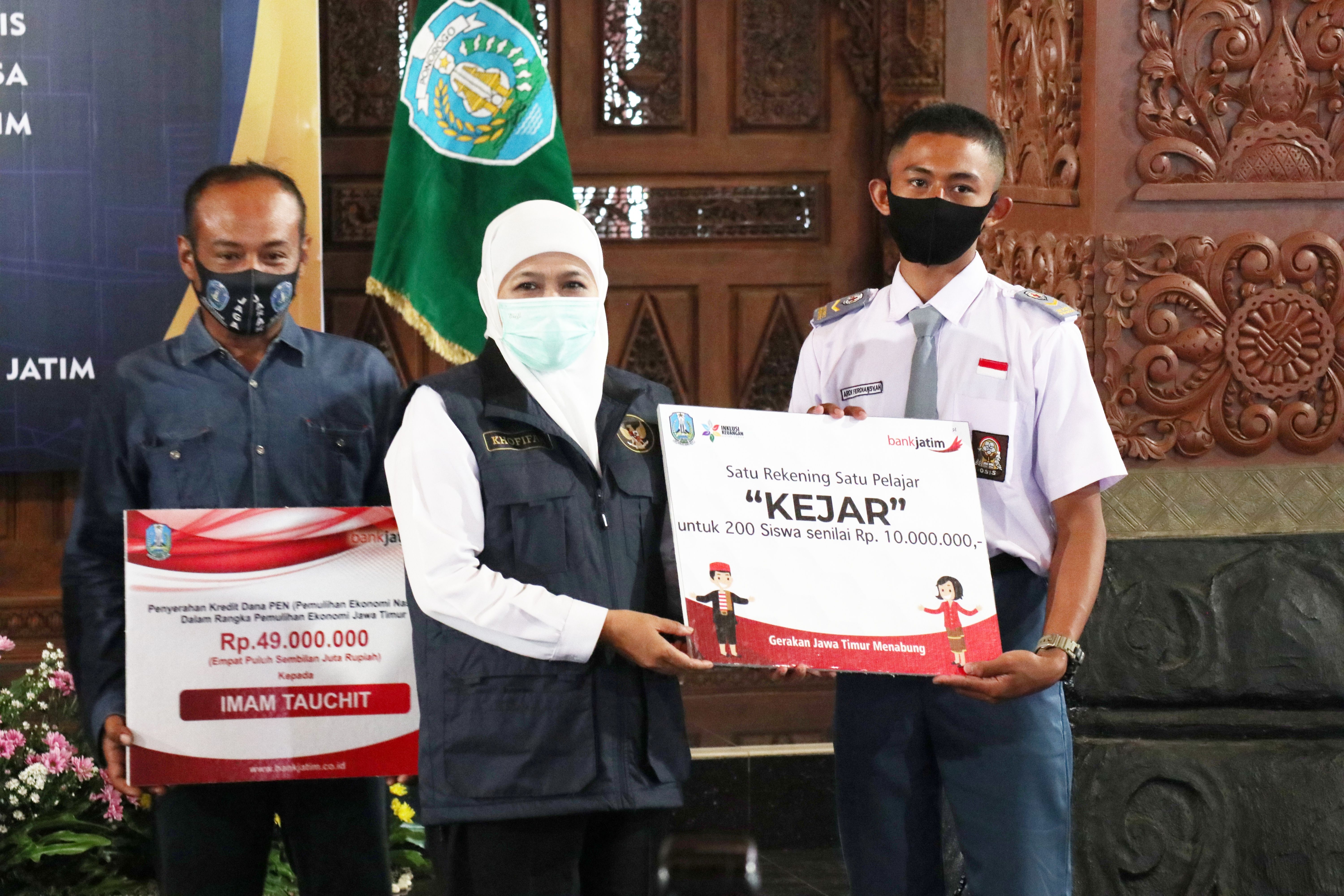 Gubernur Khofifah menyerahkan bantuan dana pendidikan secara simbolis kepada salah satu perwakilan siswa. 