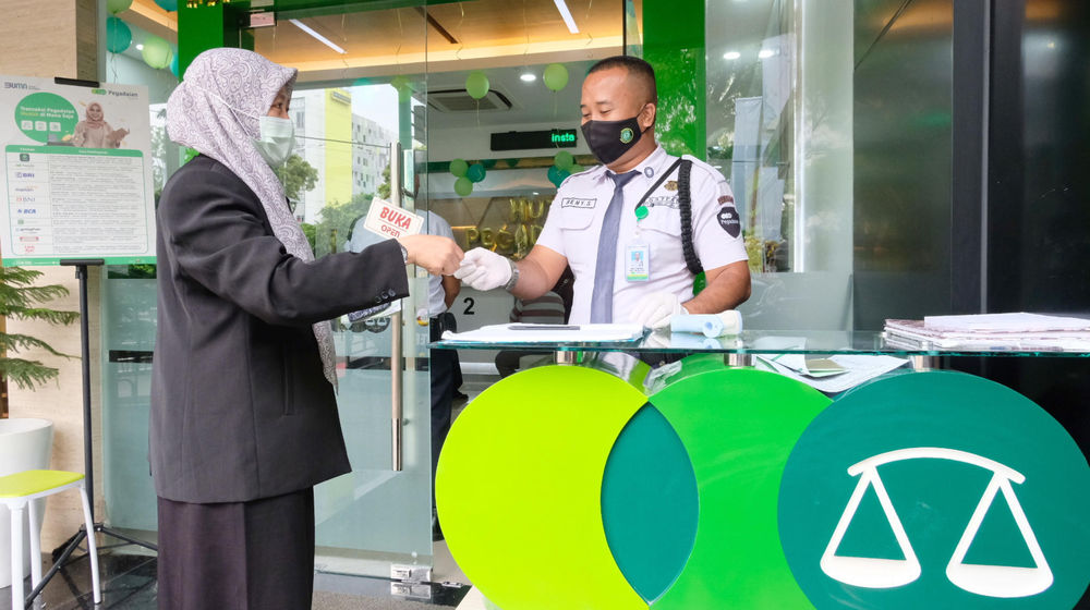 <p>Nasabah menerima nomer antrean dari petugas di kantor Pegadaian, Jakarta, Senin, 5 April 2021. Foto: Ismail Pohan/TrenAsia</p>
