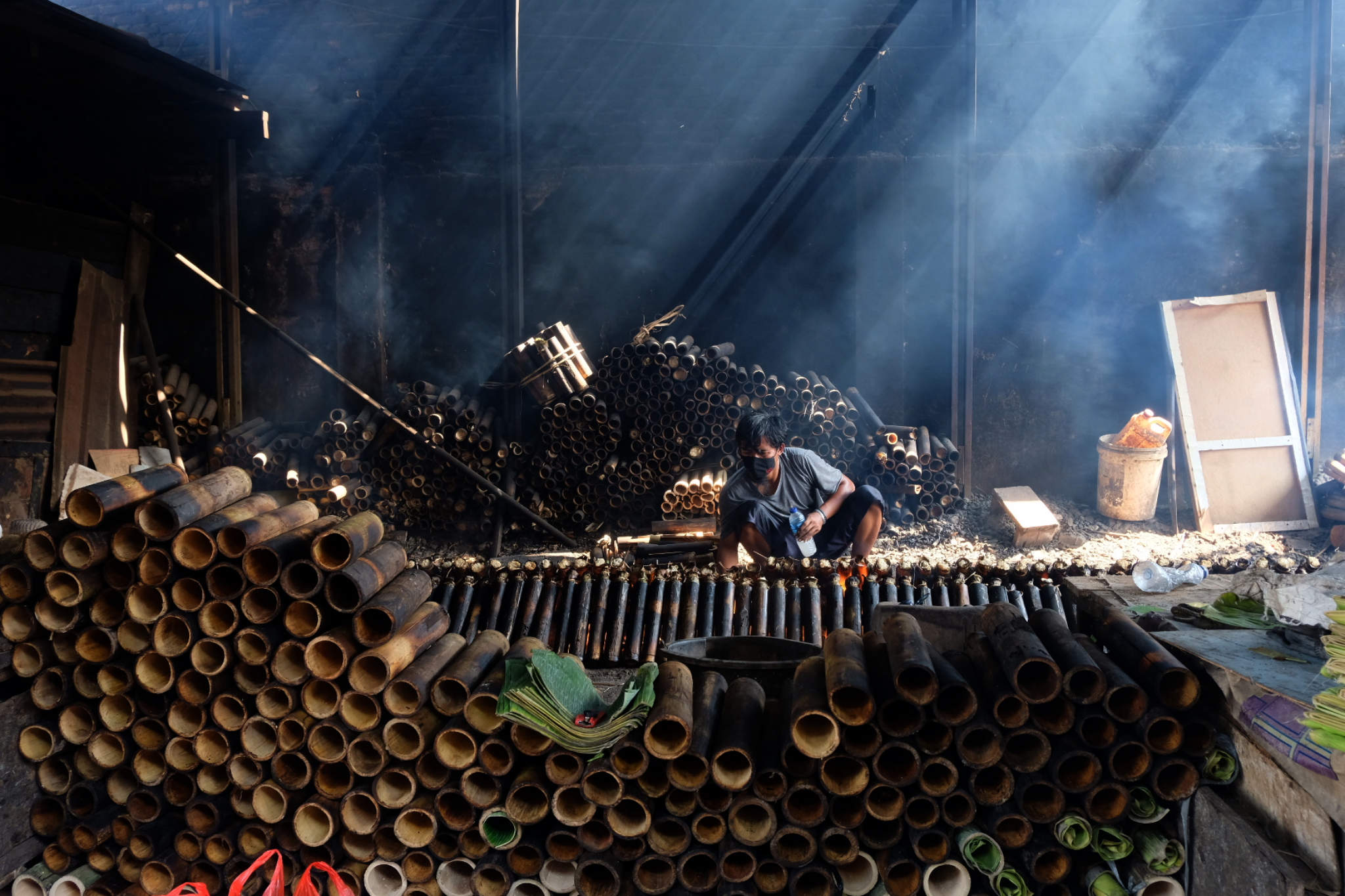 <p>Pekerja membakar lemang yang sudah dibungkus daun pisang dan dimasukkan ke dalam bambu di industri pembuatan lemang kawasan Senen, Jakarta, Selasa, 27 April 2021. Foto: Ismail Pohan/TrenAsia</p>
