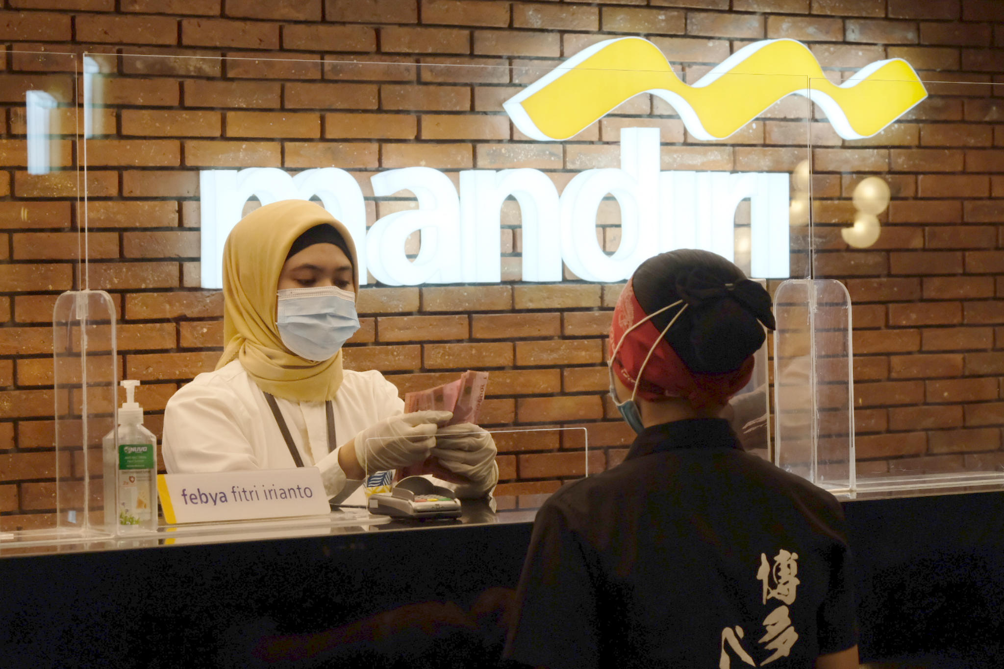 <p>Karyawan melayani nasabah di gerai salah satu cabang Bank Mandiri, di Jakarta, Selasa, 6 April 2021. Foto: Ismail Pohan/TrenAsia</p>
