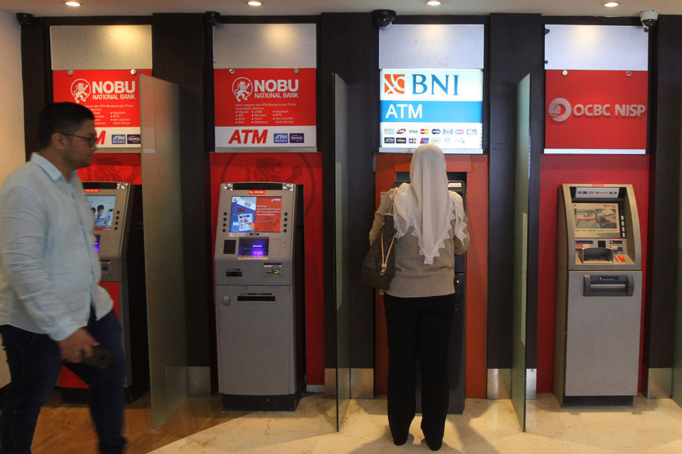Warga menggunakan fasilitas anjungan tunai mandiri (ATM) di salah satu pusat perbelanjaan di Jakarta.