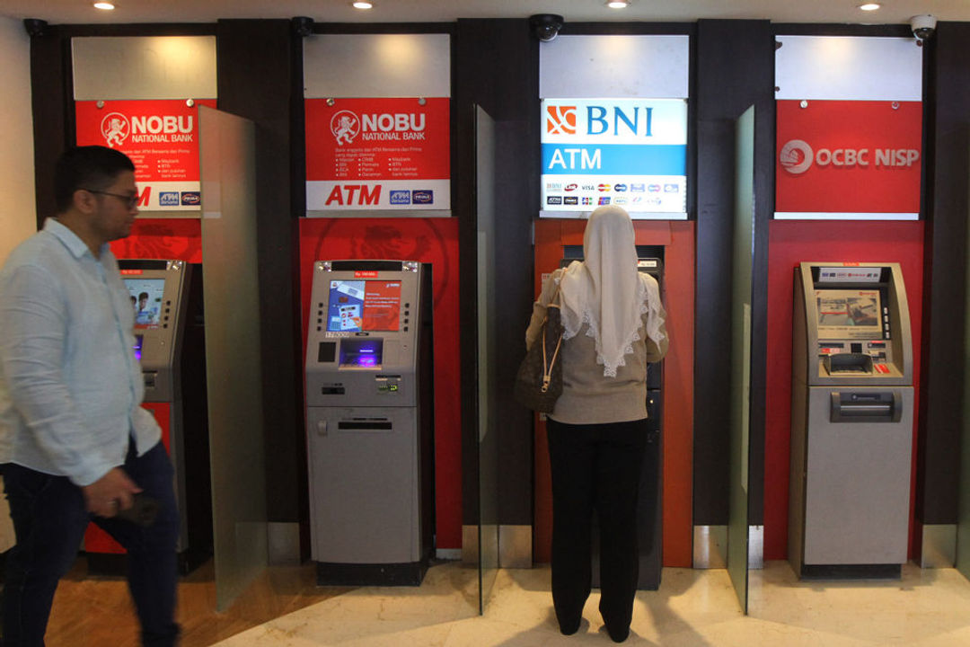 Warga menggunakan fasilitas anjungan tunai mandiri (ATM) di salah satu pusat perbelanjaan di Jakarta.