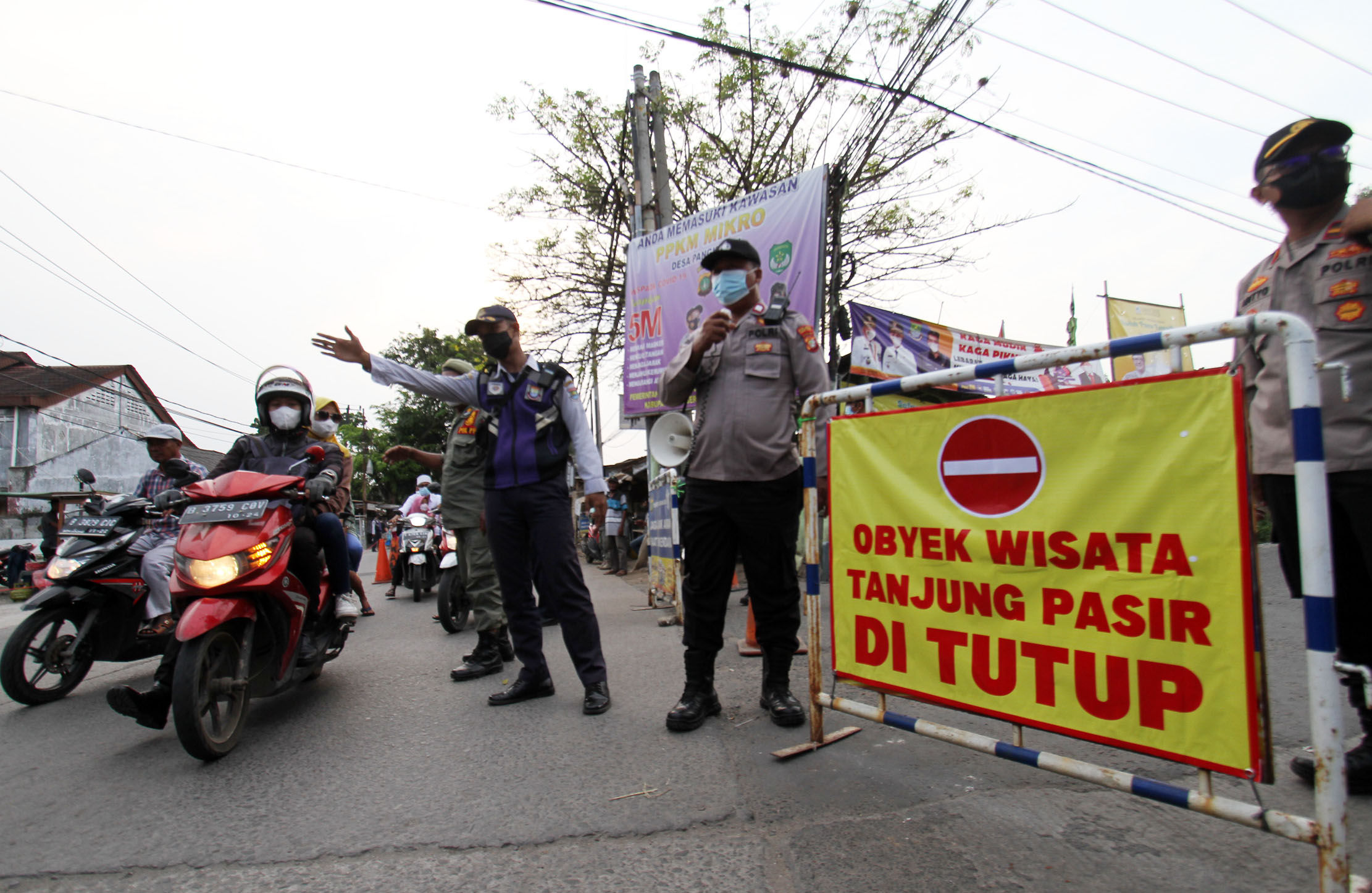 <p>Sejumlah petugas melakukan penutupan jalan menuju lokasi wisata pantai Tanjung Pasir, Kabupaten Tangerang menyusul edaran yang dikeluarkan pemerintah setempat untuk menutup wisata lokal, Minggu 16 Mei 2021. Foto : Panji Asmoro/TrenAsia</p>
