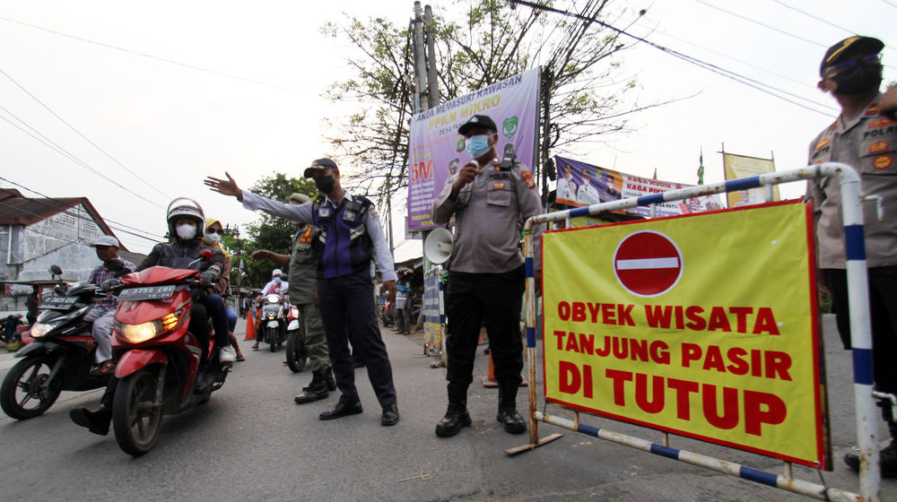 <p>Sejumlah petugas melakukan penutupan jalan menuju lokasi wisata pantai Tanjung Pasir, Kabupaten Tangerang menyusul edaran yang dikeluarkan pemerintah setempat untuk menutup wisata lokal, Minggu 16 Mei 2021. Foto : Panji Asmoro/TrenAsia</p>