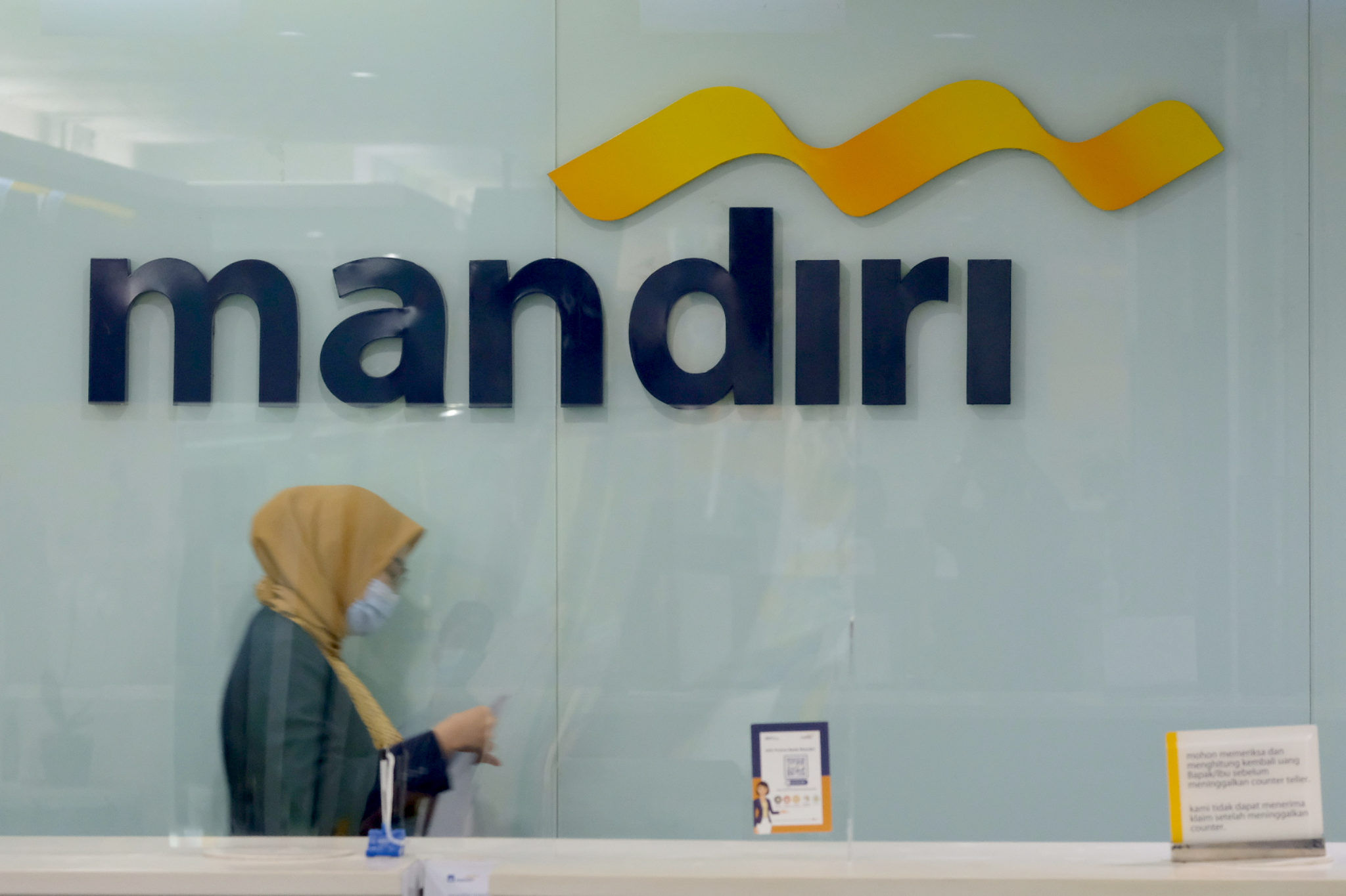 <p>Karyawan melintas di dekat logo di kantor cabang Bank Mandiri, Plaza Mandiri, Gatot Subroto, Jakarta, Selasa, 8 Juni 2021. Foto: Ismail Pohan/TrenAsia</p>
