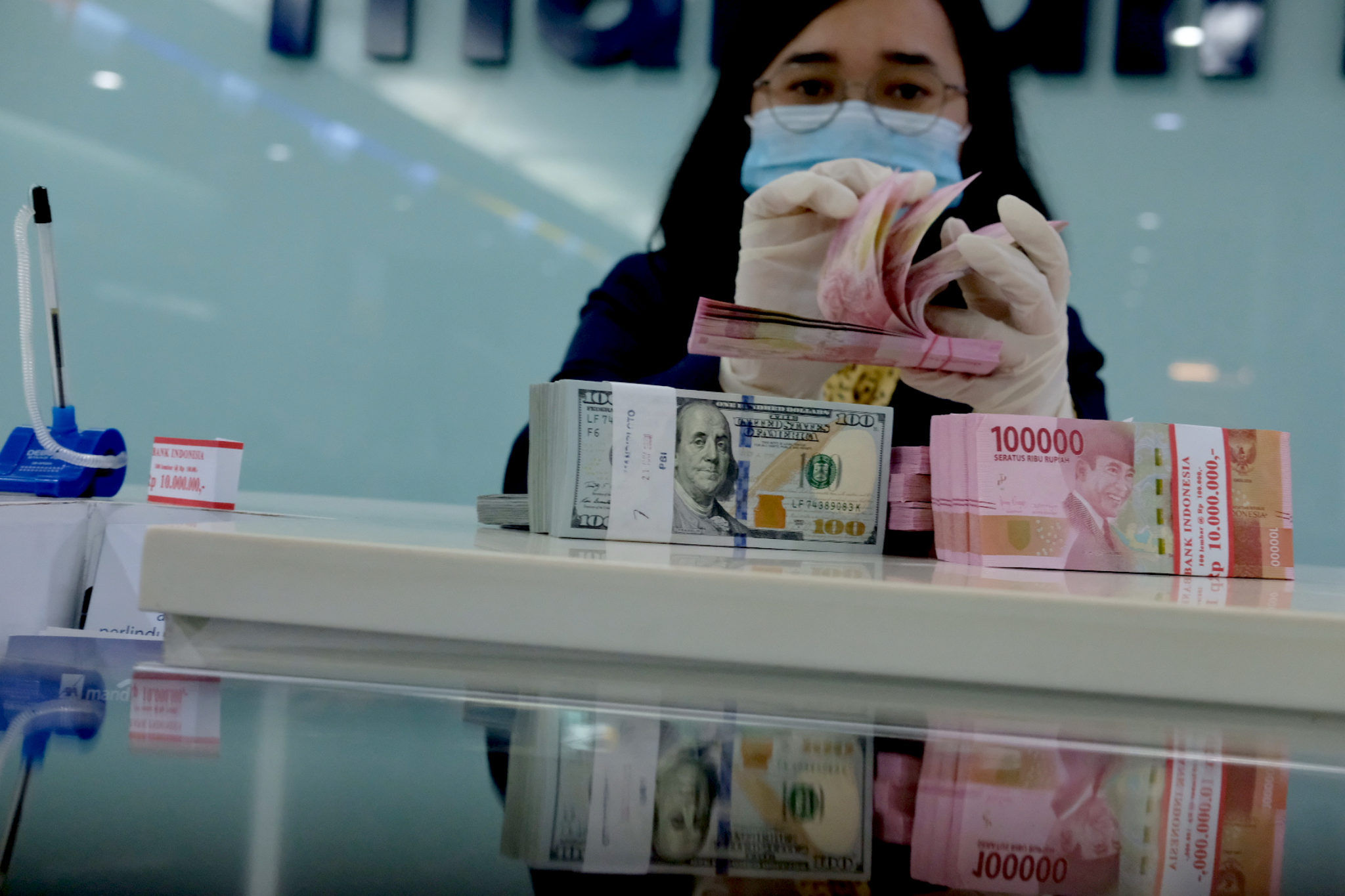 <p>Karyawati salah satu bank menunjukkan mata uang Rupiah dan Dolar di Jakarta, Selasa, 8 Juni 2021. Foto: Ismail Pohan/TrenAsia</p>
