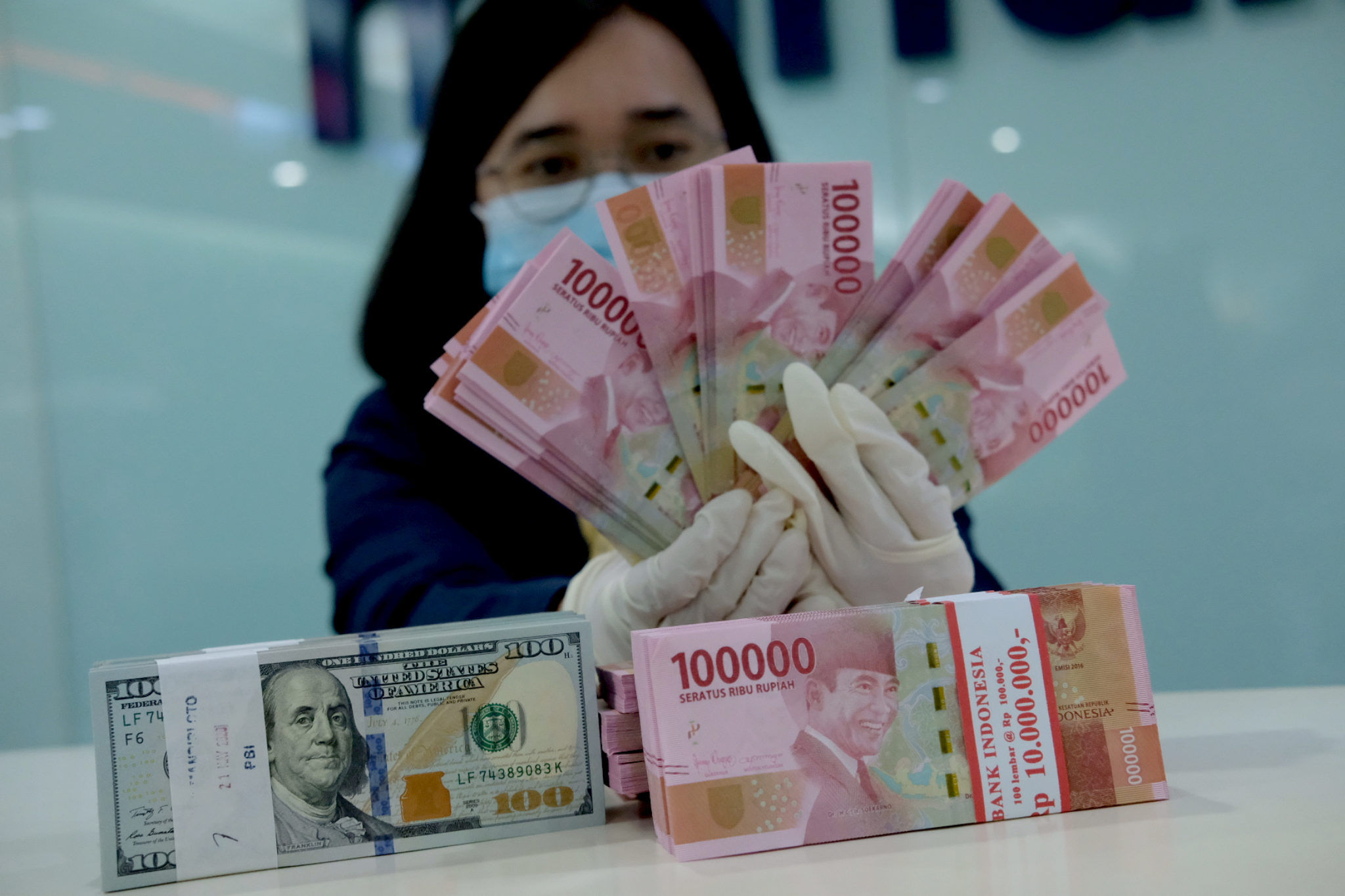 <p>Karyawati salah satu bank menunjukkan mata uang Rupiah dan Dolar di Jakarta, Selasa, 8 Juni 2021. Foto: Ismail Pohan/TrenAsia</p>
