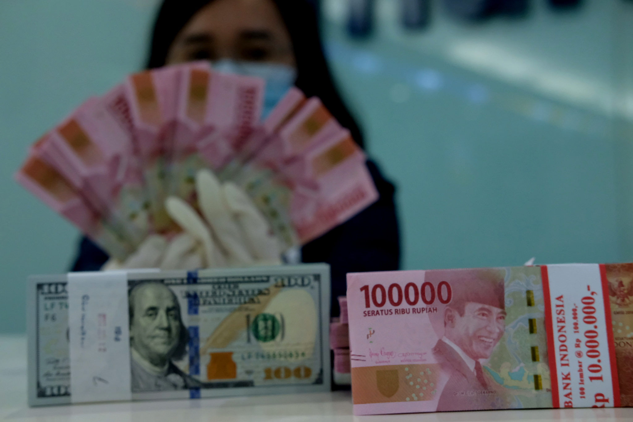 <p>Karyawati salah satu bank menunjukkan mata uang Rupiah dan Dolar di Jakarta, Selasa, 8 Juni 2021. Foto: Ismail Pohan/TrenAsia</p>
