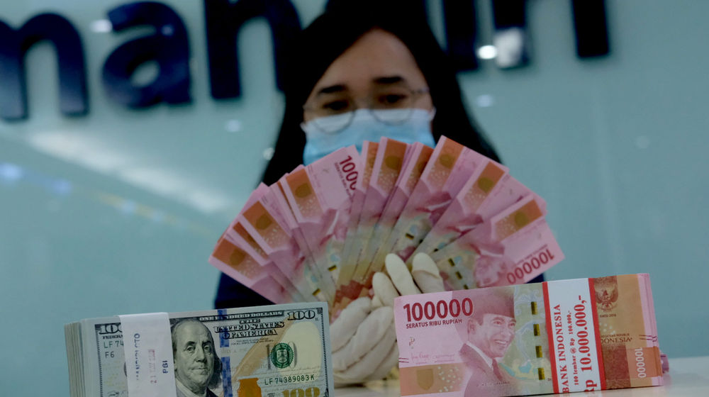 <p>Karyawati salah satu bank menunjukkan mata uang Rupiah dan Dolar di Jakarta, Selasa, 8 Juni 2021. Foto: Ismail Pohan/TrenAsia</p>