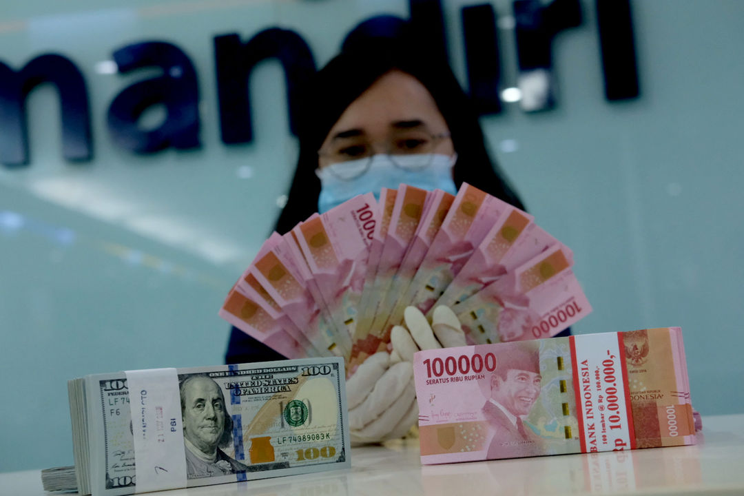 <p>Karyawati salah satu bank menunjukkan mata uang Rupiah dan Dolar di Jakarta, Selasa, 8 Juni 2021. Foto: Ismail Pohan/TrenAsia</p>
